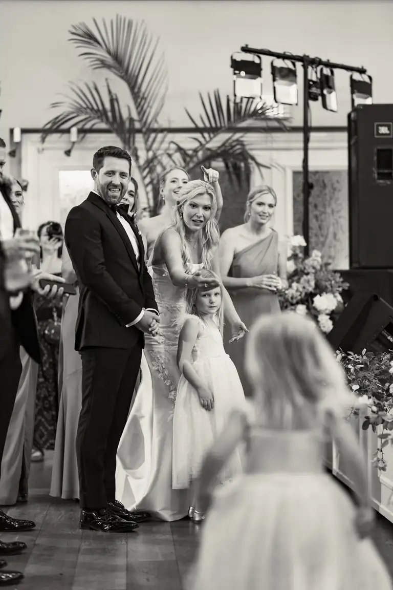 The groom and the bridal party watching the flower girl, black and white