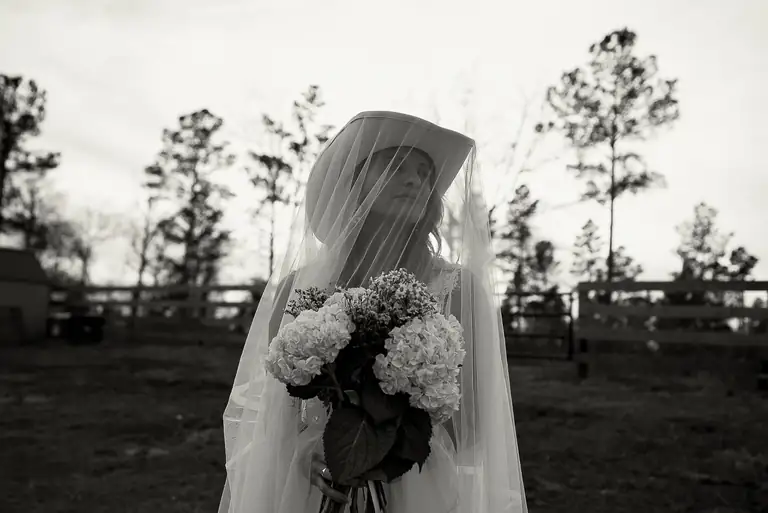 A veiled bride holding her bouquet, black and white
