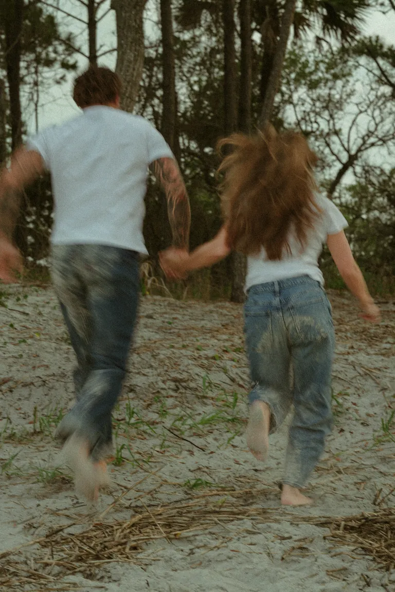 A father and daughter running hand in hand through the sand