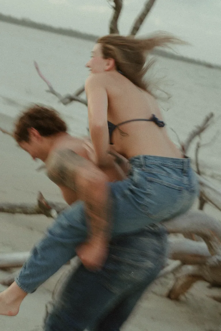 A woman carried on a man's back through the surf