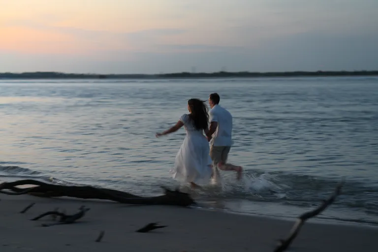 A couple running through the surf at sunset