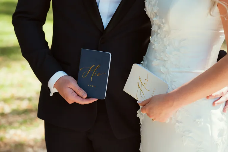 A bride and groom holding their leather vow books