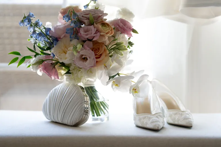 The bridal bouquet and shoes laid out in the window light