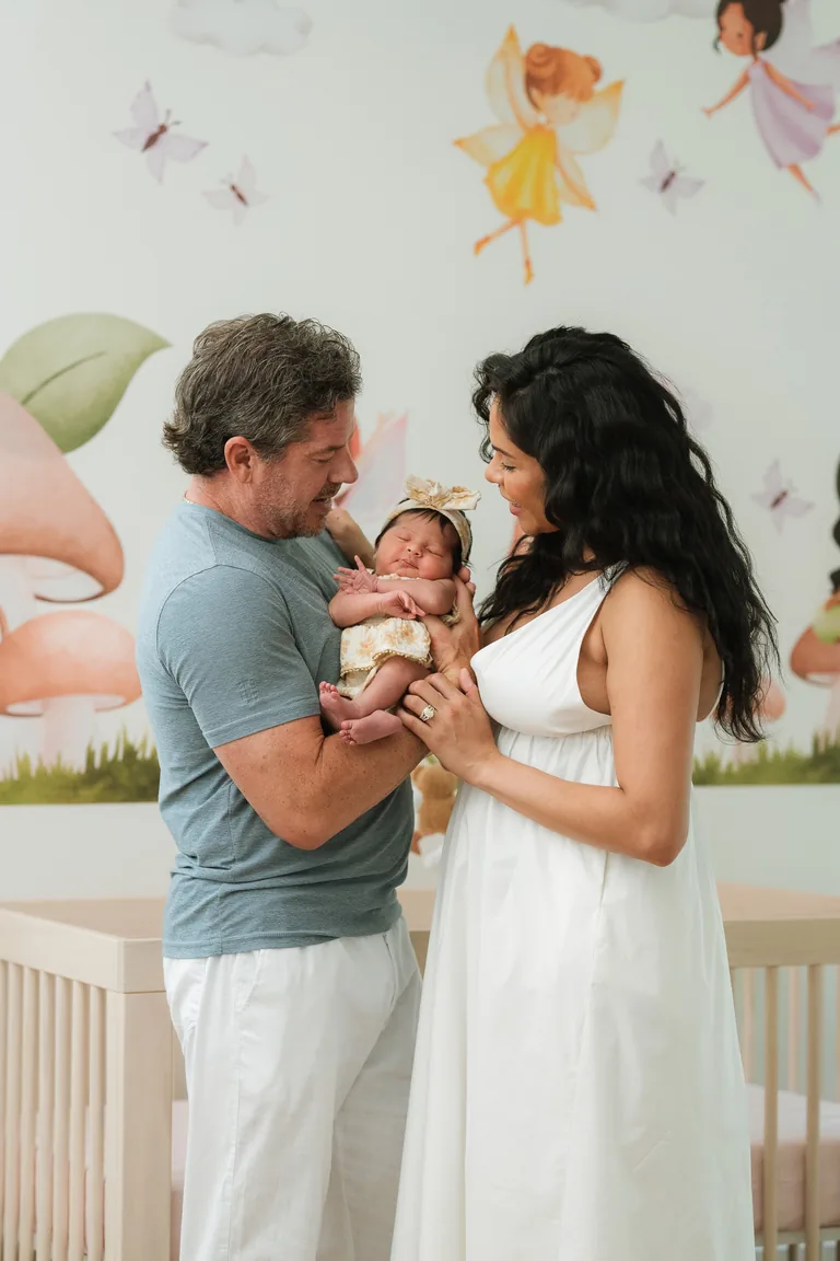 New parents standing together holding their newborn in the nursery