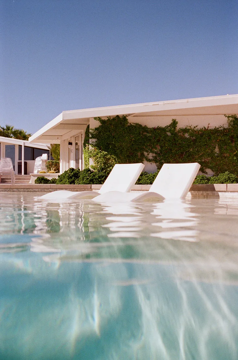 Sun loungers beside a turquoise pool at a white desert house