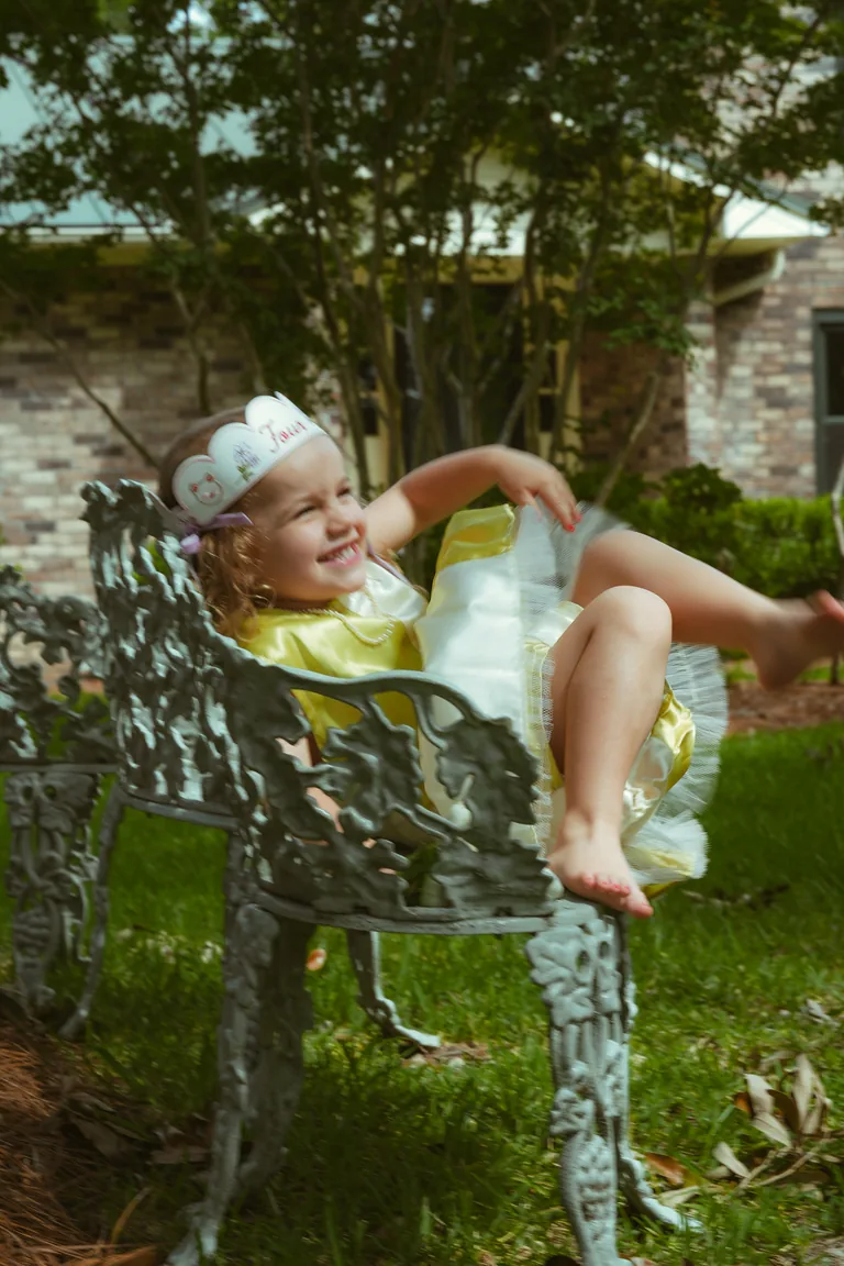 A girl in a yellow dress resting on a patterned garden bench