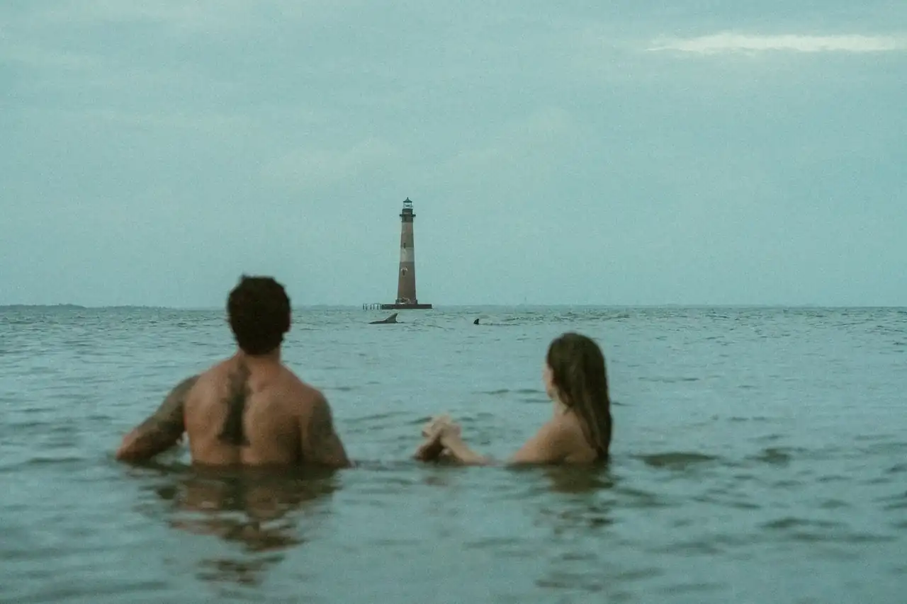 A couple in the ocean at dusk near Morris Island Lighthouse